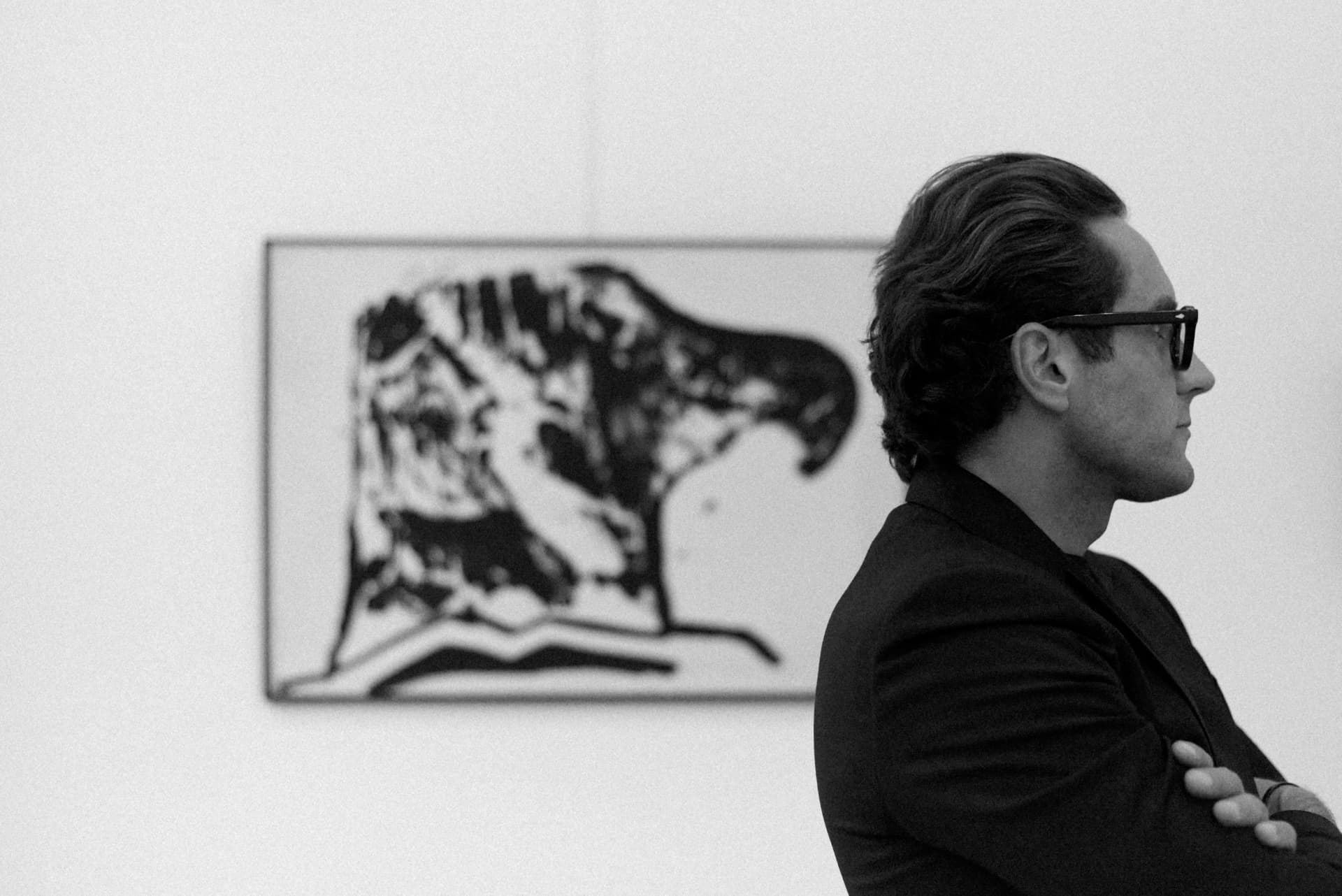 Kai Gorski in profile in a gallery, in front of a black-and-white artwork