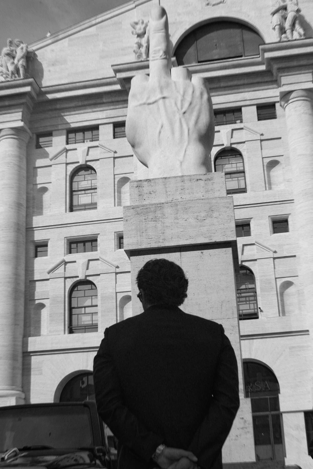 Kai Gorski seen from behind, facing a marble sculpture in front of a classical facade